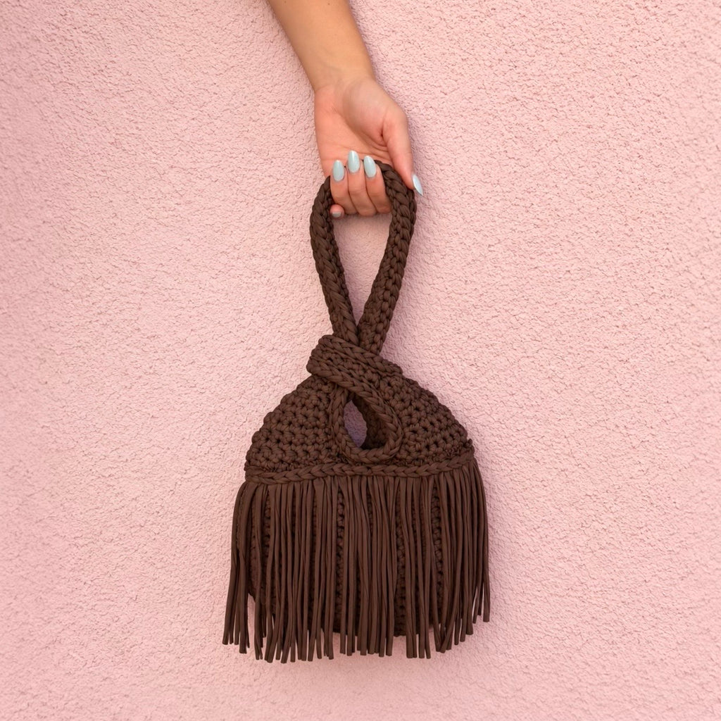 Handmade crochet mini swing bag in Coconut Shell brown with flowing fringe and a loop-through wristlet handle.
