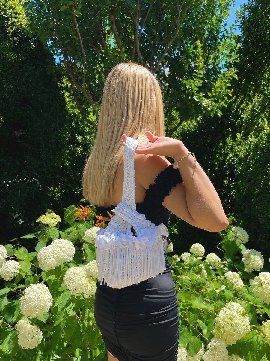 Handmade crochet mini swing bag in Gardenia white with flower fringe and a loop-through wristlet handle.
