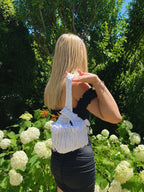 Handmade crochet mini swing bag in Gardenia white with flower fringe and a loop-through wristlet handle.