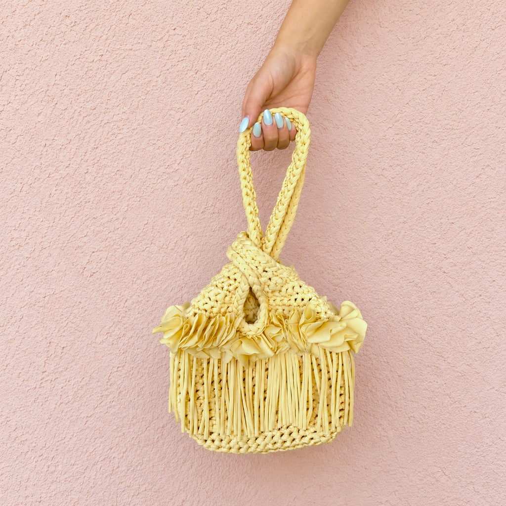 Handmade crochet mini swing bag in Daffodil light yellow with flower fringe and a loop-through wristlet handle.