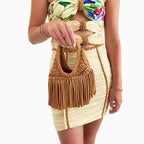 Model carrying a handmade Hazelnut brown crochet mini bag with flowing fringe and a braided handle.