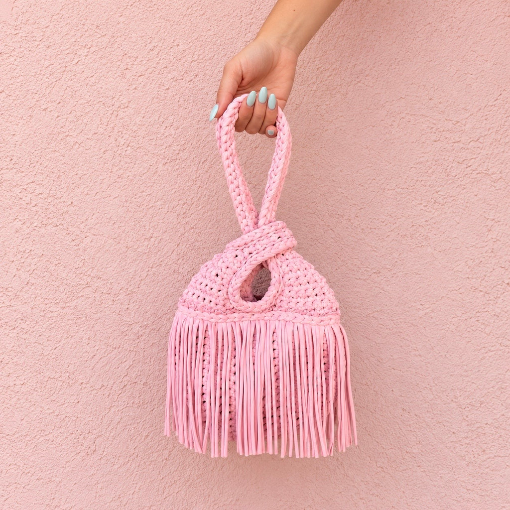 Handmade crochet mini swing bag in Petal pink with flowing fringe and a loop-through wristlet handle.