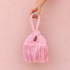 Handmade crochet mini swing bag in Petal pink with flowing fringe and a loop-through wristlet handle.