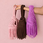Handmade crochet mini swing bags in light pink, brown and purple with flowing fringe and a loop-through wristlet handle.
