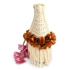 Handmade magnolia cream crochet whimsy mini bag with cascading fringe, metallic pink and copper petal bell trim and a braided handle. 