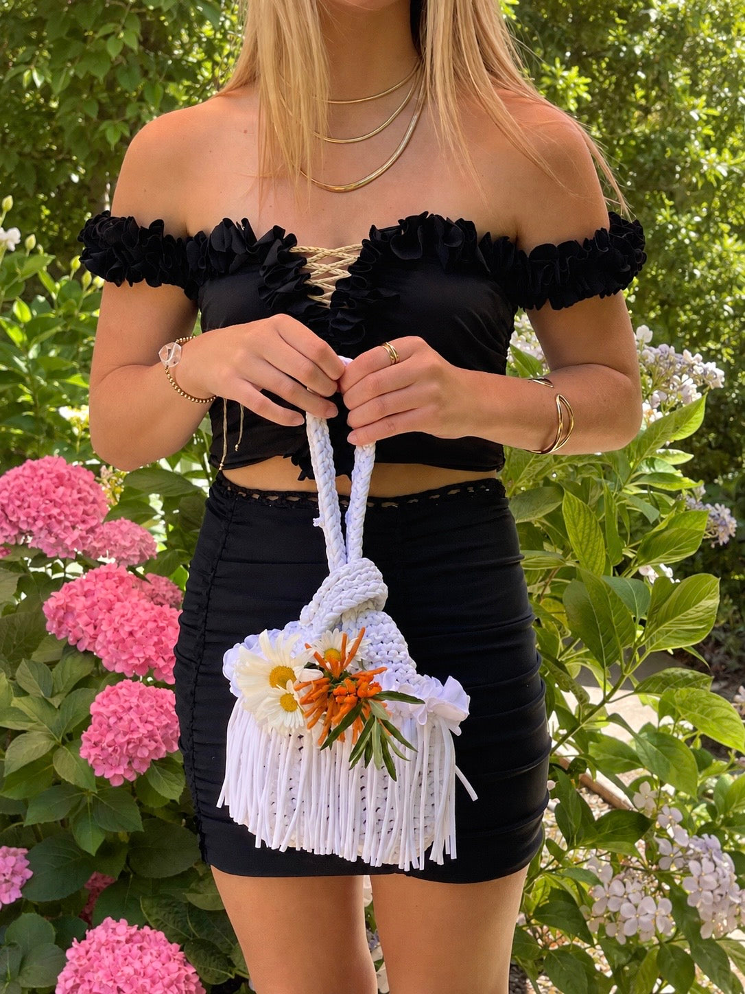 Onyx black floral off-the-shoulder crop top with flower lei trim and hand-crocheted lace-up center detail. Matching set includes the onyx black mini pencil skirt. 