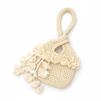 Handmade crochet petal bell mini swing bag in magnolia cream with a loop through wristlet handle and cascading petal trim. 