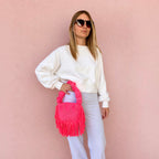 Hibiscus coral handmade crochet Cha Cha Mini bag featuring a crescent-shaped body, braided loop detailing, ruched scrunchie handle and flowing fringe. 