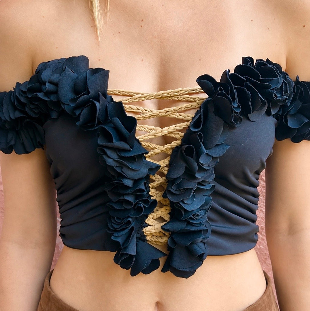 Onyx black floral off-the-shoulder crop top with flower lei trim and hand-crocheted lace-up center detail.