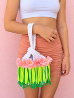 Handmade Gardenia white crochet mini swing bag with Petal pink flowers and neon yellow and green fringe with a loop-through wristlet handle.